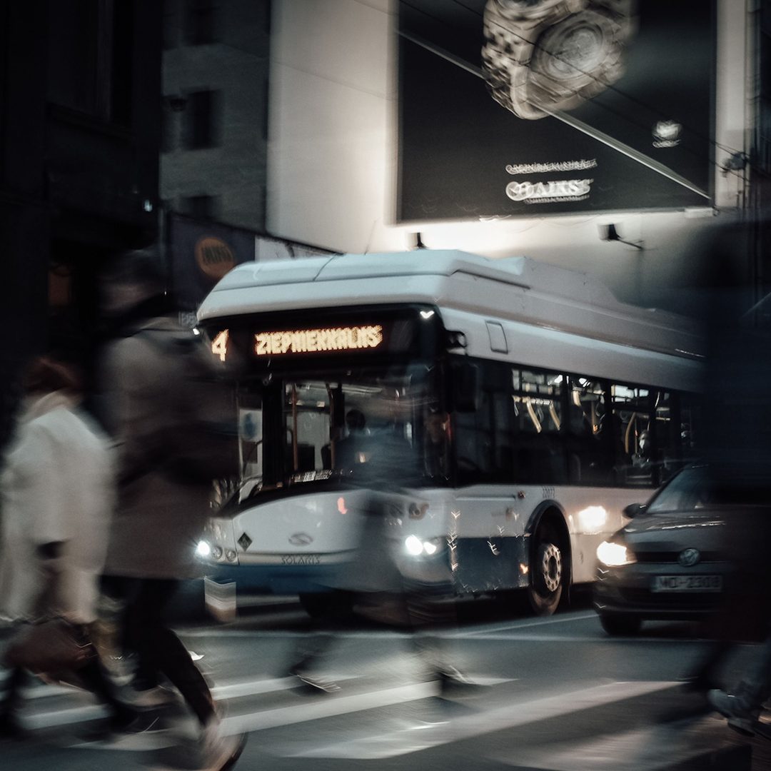 Curved digital billboard above a passing red bus